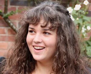 picture of a smiling young woman with curly brown hair